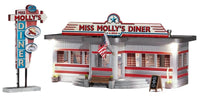 Front view of Miss Molly's Diner. Train Car type Diner  with red stripes and trim. American Flag hanging by door. wooden sign with today's special. Sign for Diner with coffee and pie on it. 