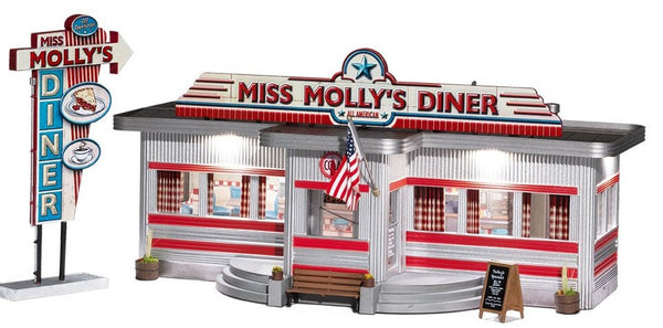 Old Fashion Diner called Miss Molly's Diner. American Flag flying outside by door. Trimmed in Red, Diner is white. Wooden sign with today's specials outside.